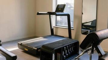 A home gym with a treadmill, exercise bike, and weights.