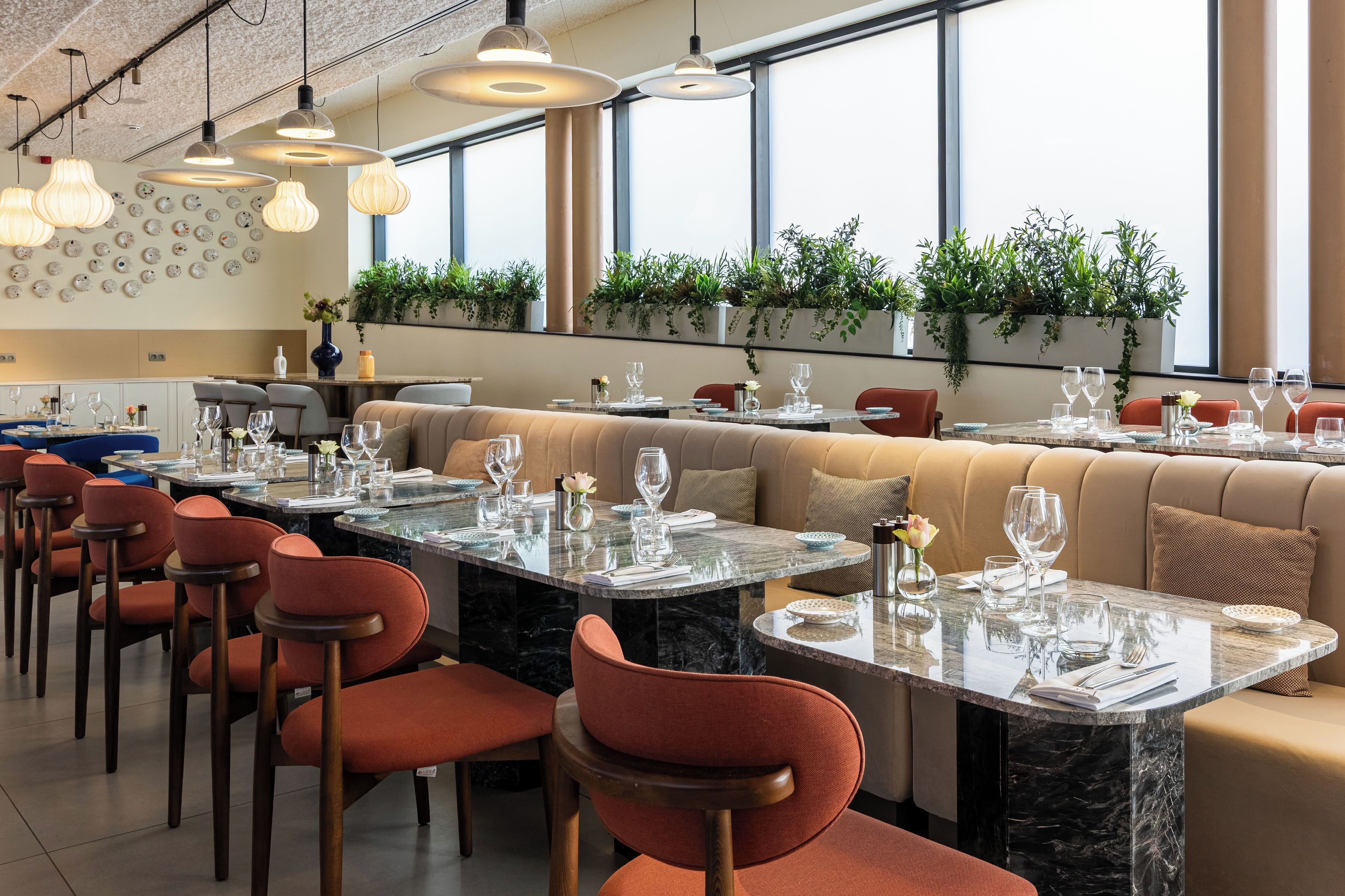 Un restaurante con una larga mesa de comedor, sillas rojas y una zona de bar.
