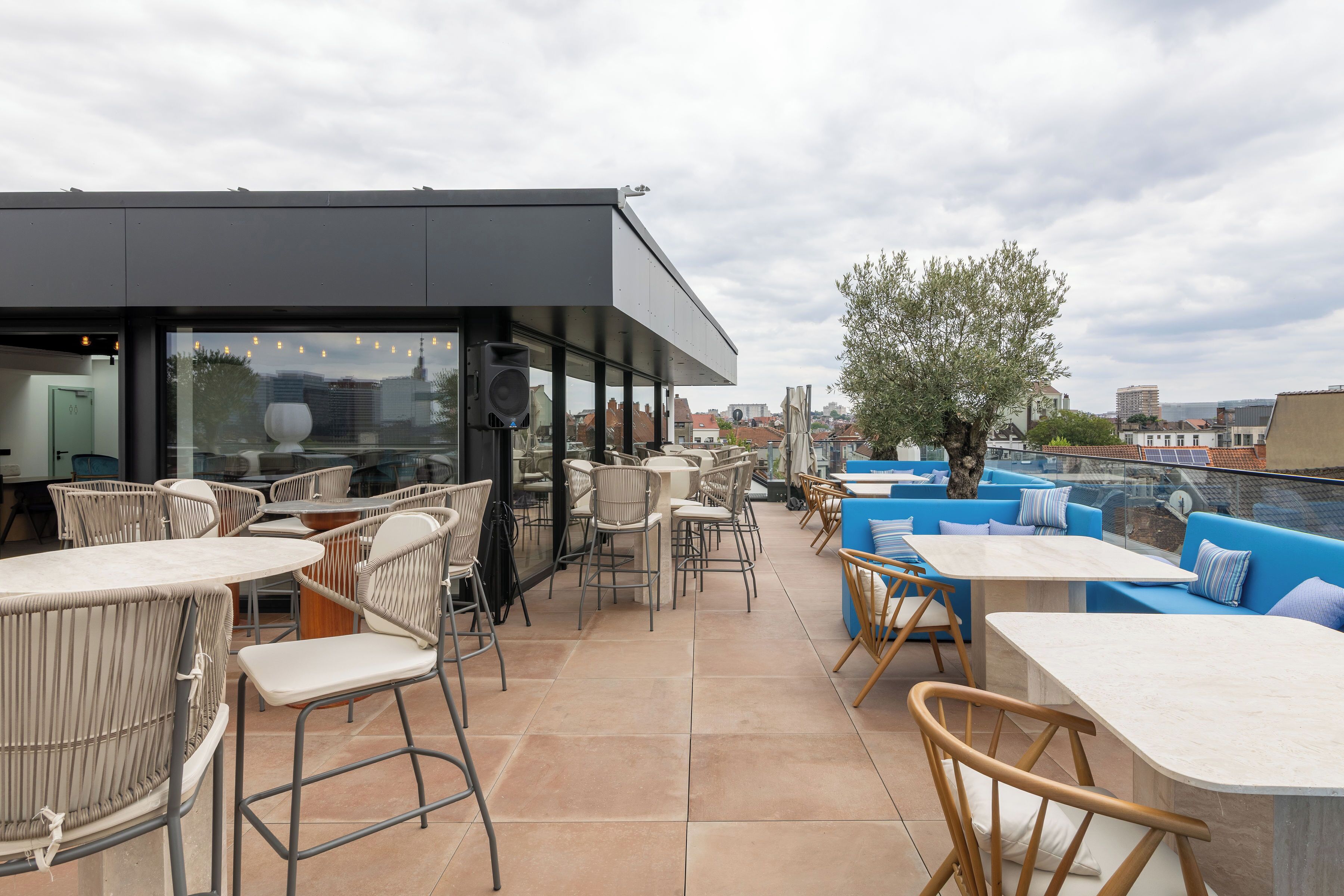 Een terras buiten met zitgedeeltes, inclusief stoelen en tafels, en een modern gebouw op de achtergrond.