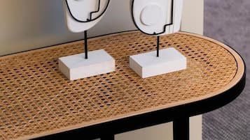 Twee witte, abstracte kunstwerken op een rond, geweven bijzettafeltje met een zwarte lijst.