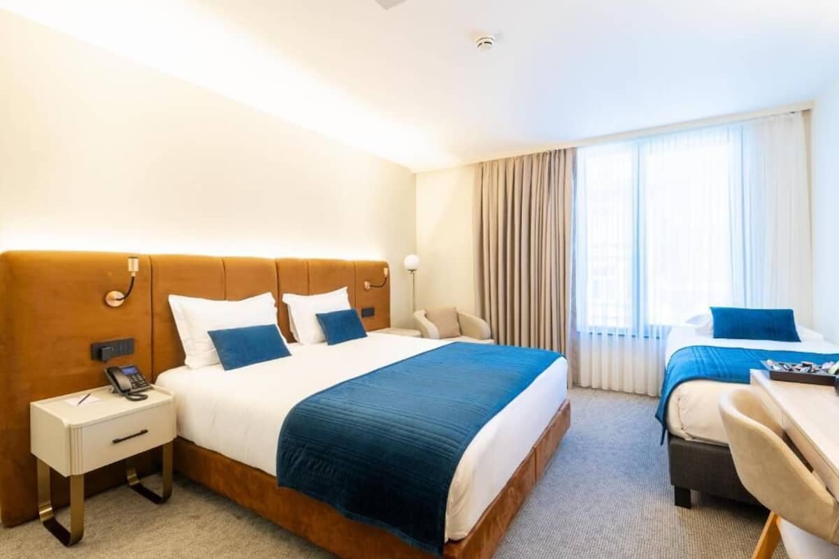 A hotel room with a large bed, bedside tables, a desk, and a chair.