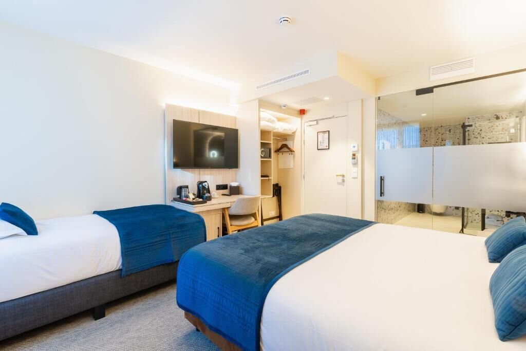 Hotelkamer met twee bedden, een bureau, een stoel, een televisie en een kledingkast.