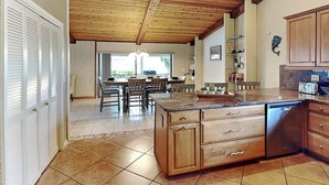 Eine geräumige Küche mit Holzschränken, einer zentralen Kochinsel und einem Essbereich mit Stühlen und Tisch.