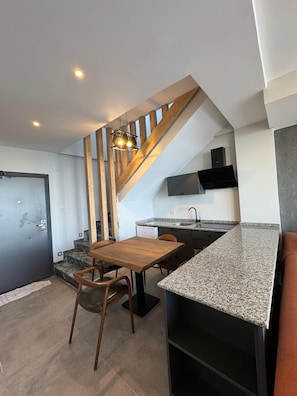 A modern kitchen with granite countertops, a wooden dining table, and a built-in oven. - NORTH STAR RESORT HOTEL (Of)