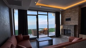 A modern living room with a large window, a fireplace, and a stone accent wall. - NORTH STAR RESORT HOTEL (Of)