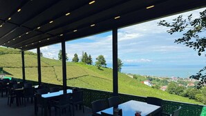 A terrace with tables and chairs, overlooking a hilly landscape and the sea. - NORTH STAR RESORT HOTEL (Of)