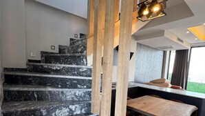 A modern staircase with marble steps leading to a wooden-framed landing. A contemporary light fixture hangs above the landing. - NORTH STAR RESORT HOTEL (Of)