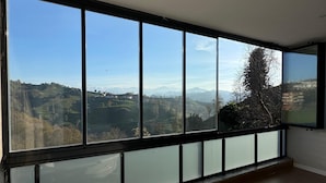 A room with a large bathtub, a balcony with a view of a mountainous landscape, and a large window. - NORTH STAR RESORT HOTEL (Of)
