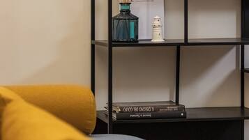 A modern living room with a black bookshelf, a blue vase with reed sticks, and a white candle.