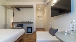 Habitación de hotel con cama, sofá, una mesita, televisor y minibar.