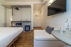 Habitación de hotel con cama, sofá, una mesita, televisor y minibar.