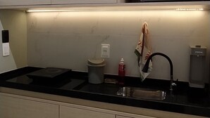 A modern kitchen with a black countertop, a built-in microwave, and a sink. - Amazing apartment in Porto de Galinhas with stunning views close to the center (Porto de Galinhas Ipojuca)