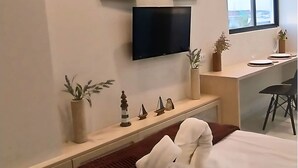 A hotel room with a bed, a desk, a TV mounted on the wall, and a window. - Amazing apartment in Porto de Galinhas with stunning views close to the center (Porto de Galinhas Ipojuca)