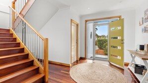 A modern interior with a wooden staircase, a round woven rug, and a glass door leading outside.