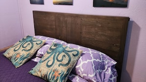 Un letto con una testiera in legno, due cuscini decorativi e tre quadri appesi al muro.