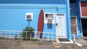Un edificio blu con un murale raffigurante una tavola da surf, una porta bianca e una piccola finestra.