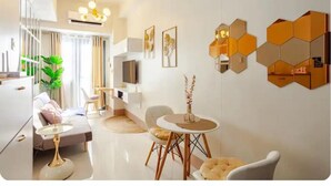 Een moderne woonkamer met een bank, salontafel en stoelen, een televisie en een decoratief wandobject.