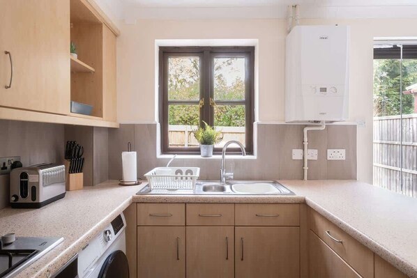 A kitchen with a built-in washing machine, a window with a view, and a water heater.