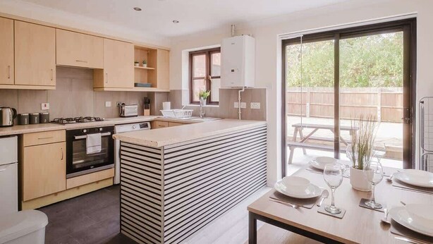 Una cucina moderna con isola centrale, mobili a scomparsa e zona pranzo con tavolo apparecchiato per due.