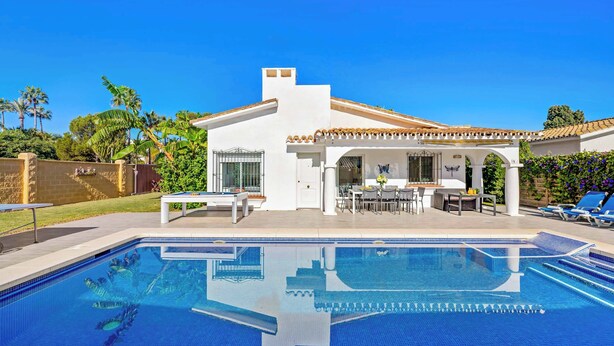 Una casa moderna con piscina, mobili da patio e una zona esterna coperta.