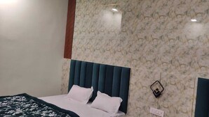 A bedroom with a bed, a marble-patterned wall, and a power outlet. - Hotel Relaxx Luxury (Amritsar)