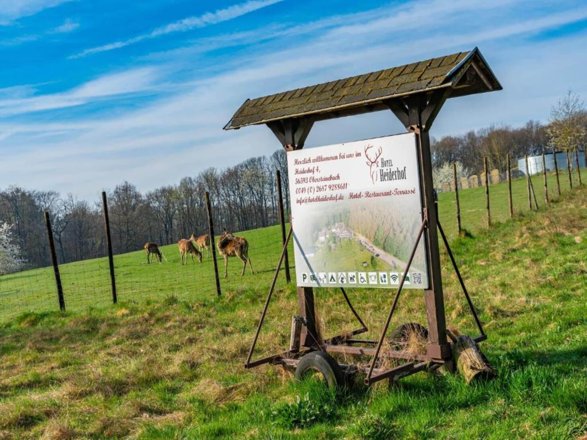 A rustic wooden sign with contact information for a hotel in a rural setting.