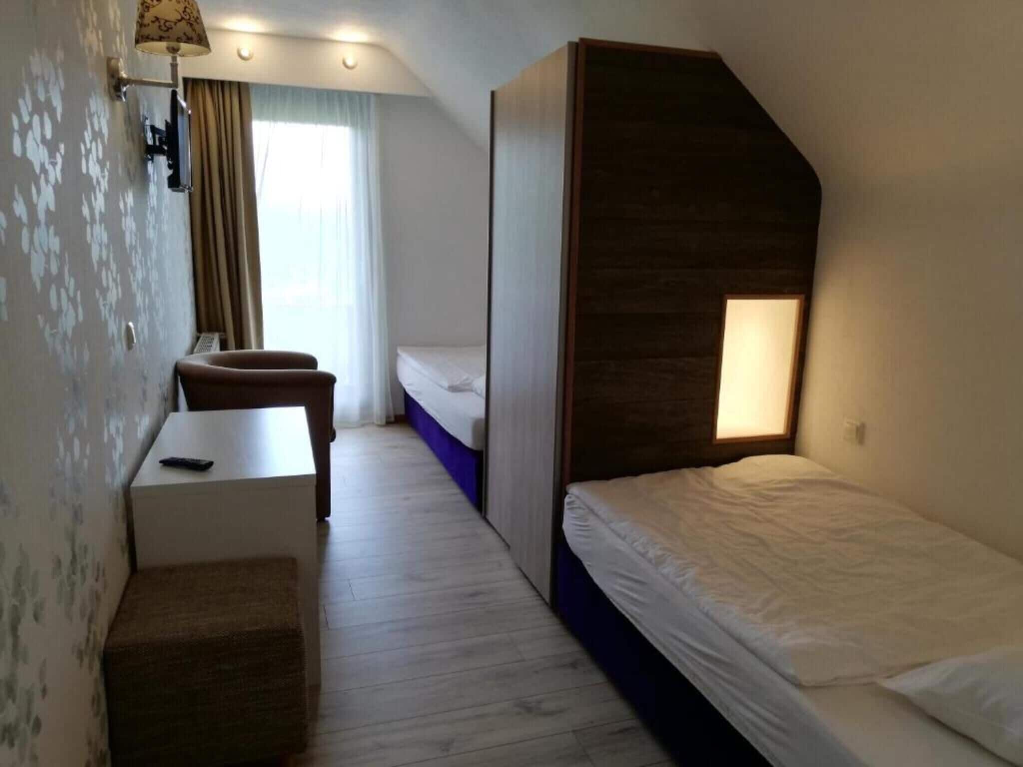 A compact hotel room with a bed, a desk, and a chair.