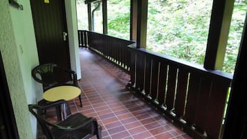 A covered outdoor area with a tiled floor, a wooden railing, and two chairs.