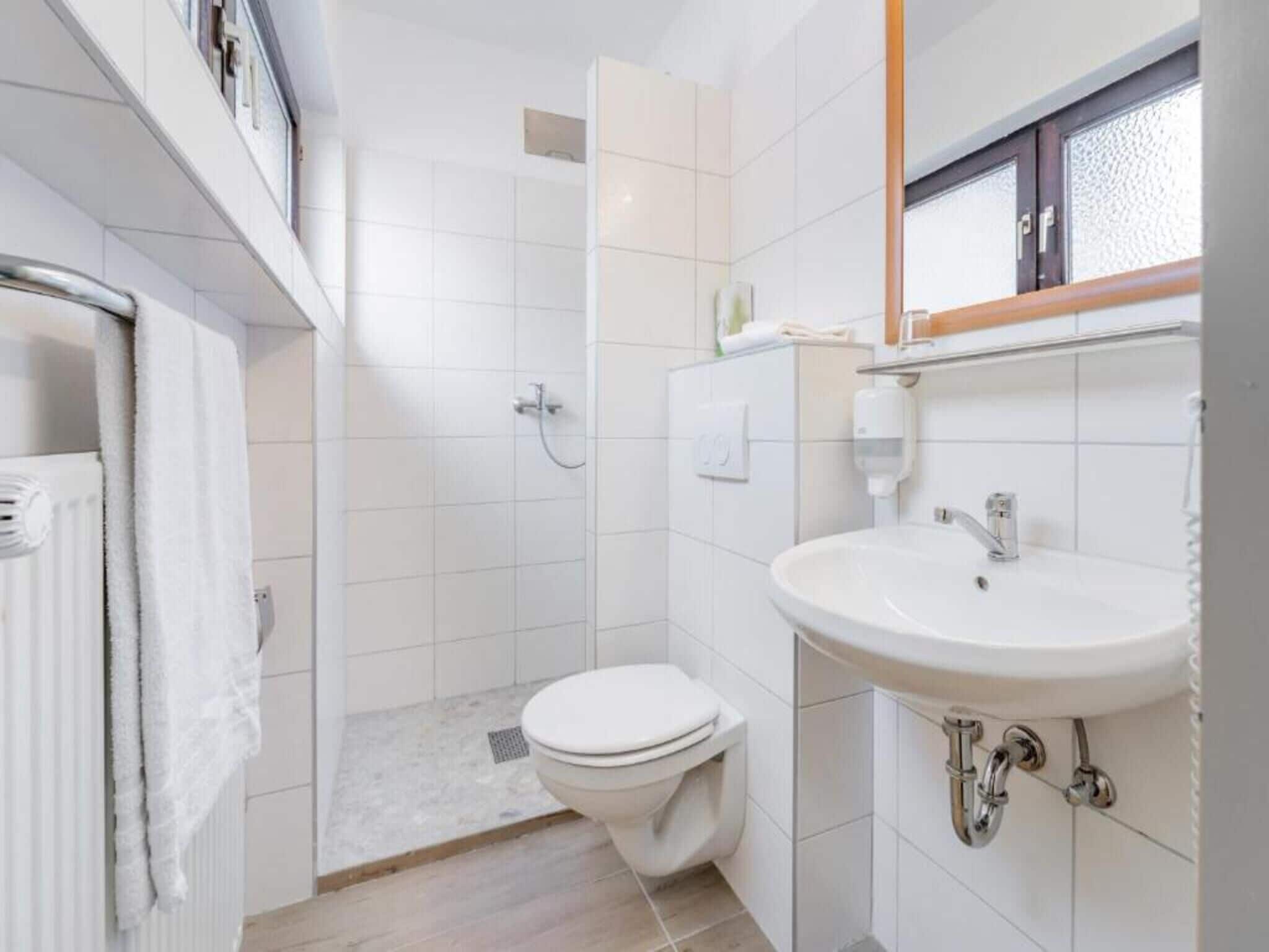 Baño con inodoro blanco, lavamanos y ducha.
