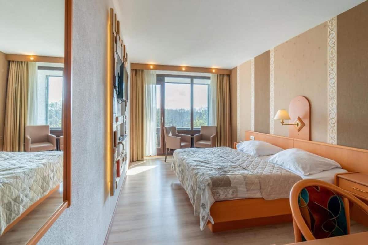 Hotellihuone, jossa on kaksi sänkyä, televisio, työpöytä ja tuoli.