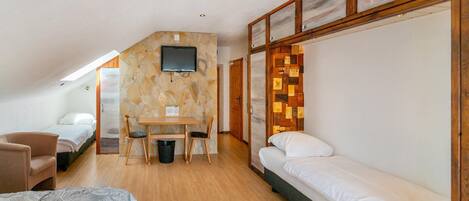 A compact, well-lit room with a bed, a desk, and a chair.