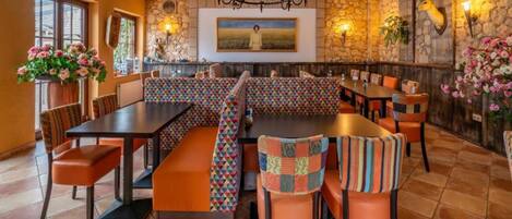 A restaurant with a stone wall, a chandelier, and a painting on the wall.