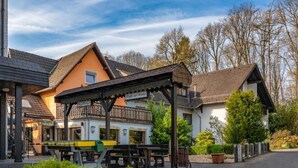Un bâtiment doté d’une terrasse extérieure couverte, d’une façade blanche et d’un toit brun.