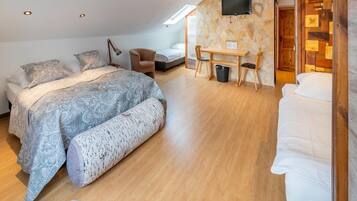 Un dormitorio con cama, escritorio, silla, televisor y pared de piedra.
