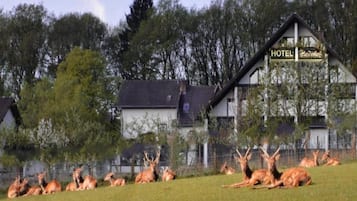 Ein Hotel mit einem Schild, umgeben von einer Wiese mit Hirschen.