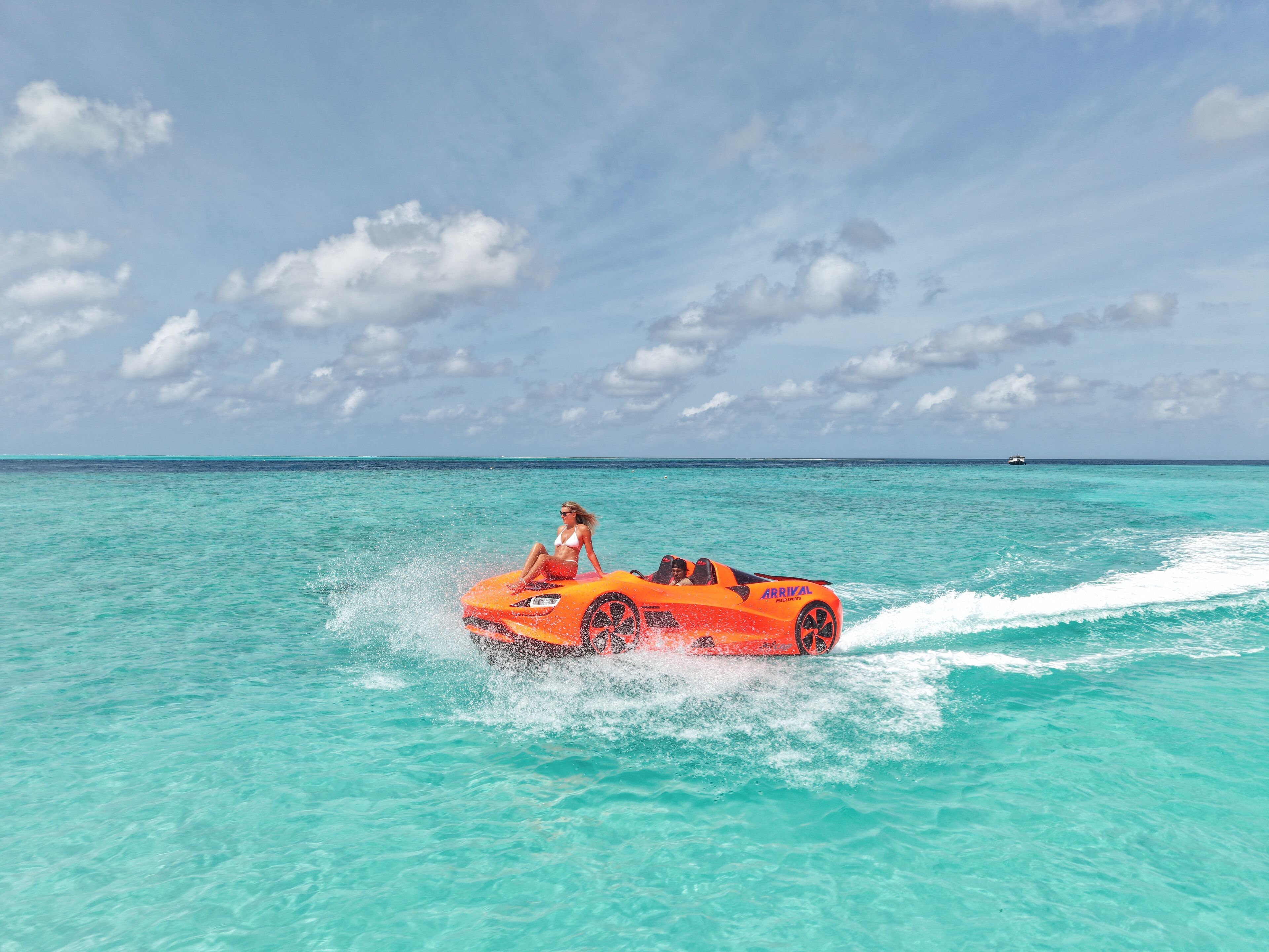 Eine Person fährt in einem Cabrio über türkisfarbenes Wasser.