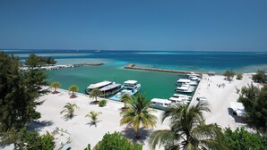 Un puerto deportivo con barcos amarrados, una playa de arena y un cielo azul despejado.