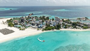 Vista aérea de un pueblo costero con playa, aguas turquesas cristalinas y una combinación de edificios residenciales y comerciales.