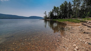 A clear lake with a rocky shoreline and dense forest in the background.