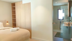 A bedroom with a bed, a wooden wardrobe, and a bathroom with a shower and sink. - Two Bedroom Villa (Porches)
