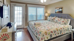 A bedroom with a bed, a desk, a ceiling fan, and a painting on the wall. - Fantasea Cove by Silver Sands Vacation Rentals (Port Aransas)
