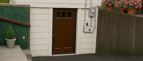 Une maison à deux étages avec une porte d’entrée marron, un petit porche et une allée en béton.