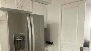 A kitchen with a stainless steel refrigerator, white cabinets, and a wooden floor. - Modern 2BR Near NYC • Free Parking • Quiet Area (Yonkers)