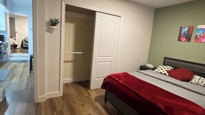 A bedroom with a bed, a closet, and a hallway leading to another room. - Modern 2BR Near NYC • Free Parking • Quiet Area (Yonkers)