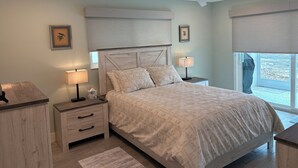 Un dormitorio con cama, mesitas de noche, ventilador de techo y ventana con vistas.