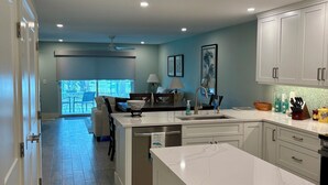 Una cocina moderna con una isla grande, armarios blancos y vistas al exterior.