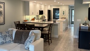 Una cocina moderna con armarios blancos, un área de comedor con un sofá blanco y vistas al salón.