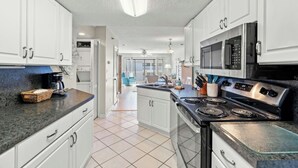 A modern kitchen with white cabinets, a stainless steel stove, and a microwave. - Grove Pointe 303-2BR/2BA-2nd Row-Oceanview (North Myrtle Beach)