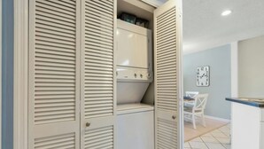 A compact kitchen with a built-in oven and a dining area with a white table and chairs. - Grove Pointe 303-2BR/2BA-2nd Row-Oceanview (North Myrtle Beach)