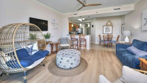 A modern living room with a sofa, a chair, a round ottoman, a dining area with chairs, a kitchen in the background, and a ceiling fan. - Horizon PH2 -2BR/2BA -Myrtle Beach -I/O Pools (Myrtle Beach)